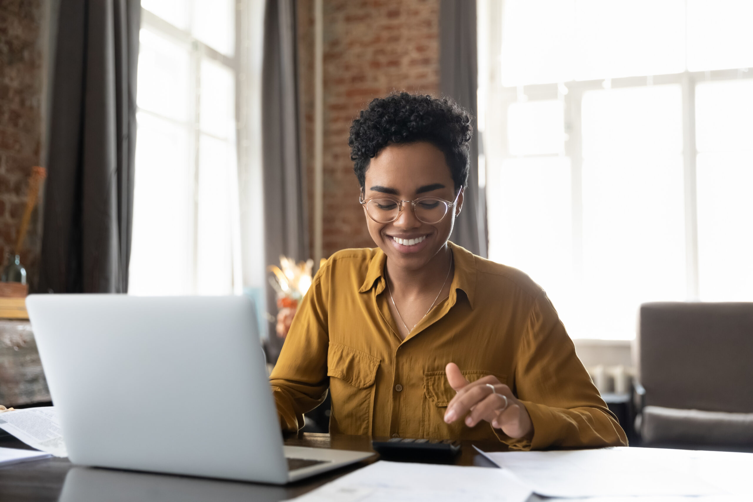 Smiling real estate investor working at desk with laptop and calculator