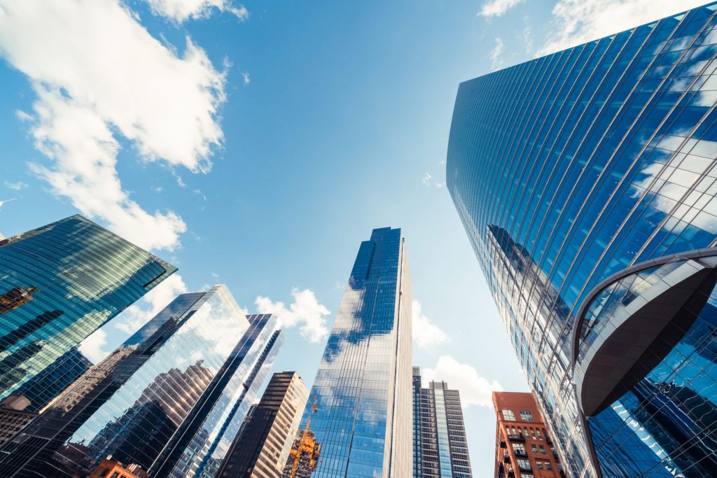 Modern commercial buildings set against a blue sky with clouds