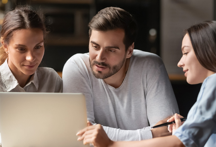 Team of real estate investors gathered around a laptop reviewing data together