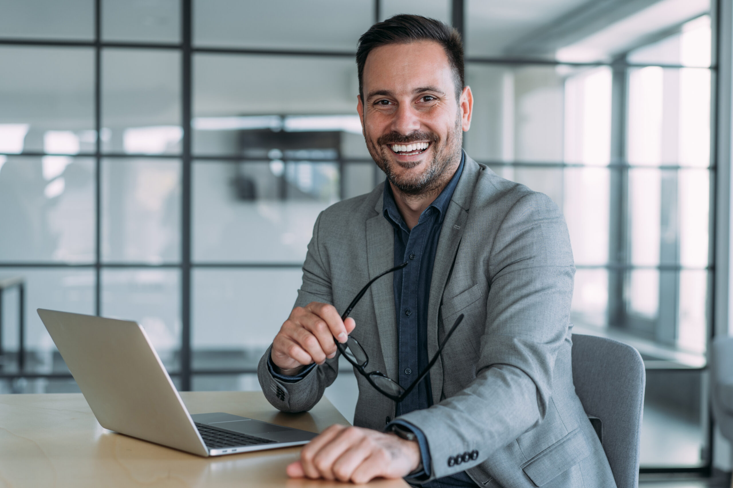 Smiling real estate investor in office with open laptop